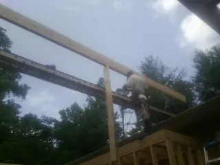 Carpenter setting a ridge beam over a new addition frame — Ice Dam Removal by Roofing Brothers in Euless
