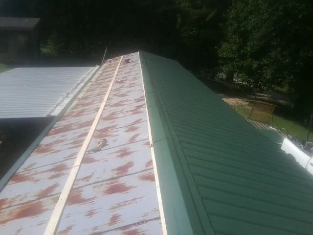 Old rusted panels beside newly installed green metal roofing — Wind Damage Roof Repair by Roofing Brothers in Euless