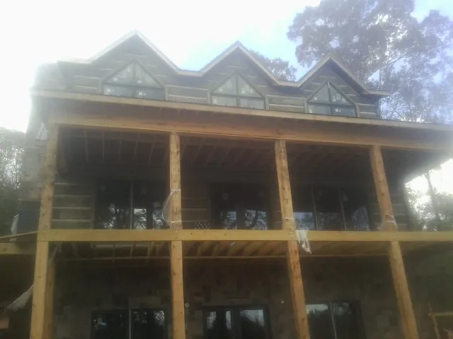 Dormers and porch framing on a large log home under construction — Roof Coating work by our crew in Euless