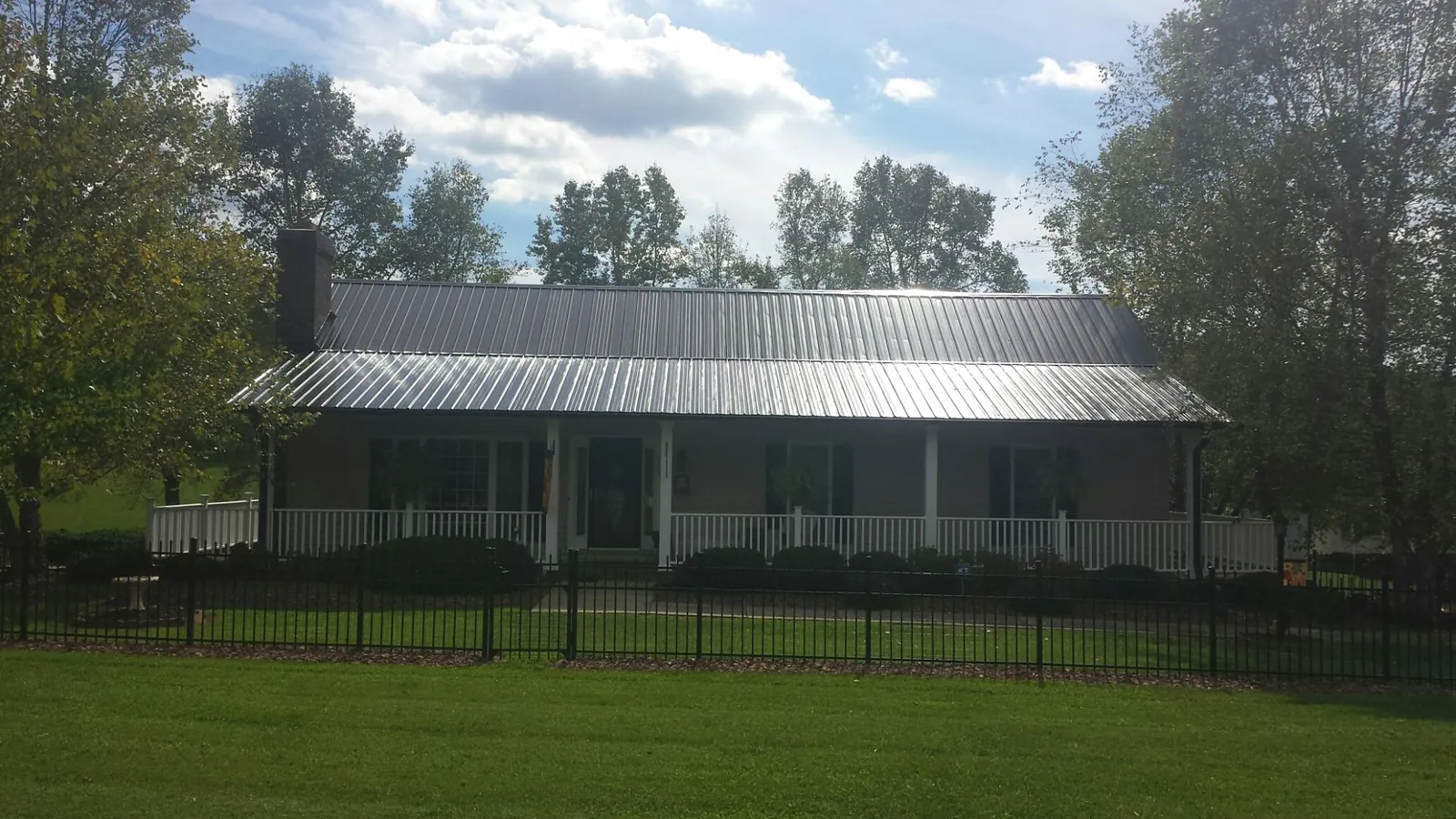 Gray metal roof on a brick ranch with a full width front porch — Gutter Guard Installation work by our crew in Euless
